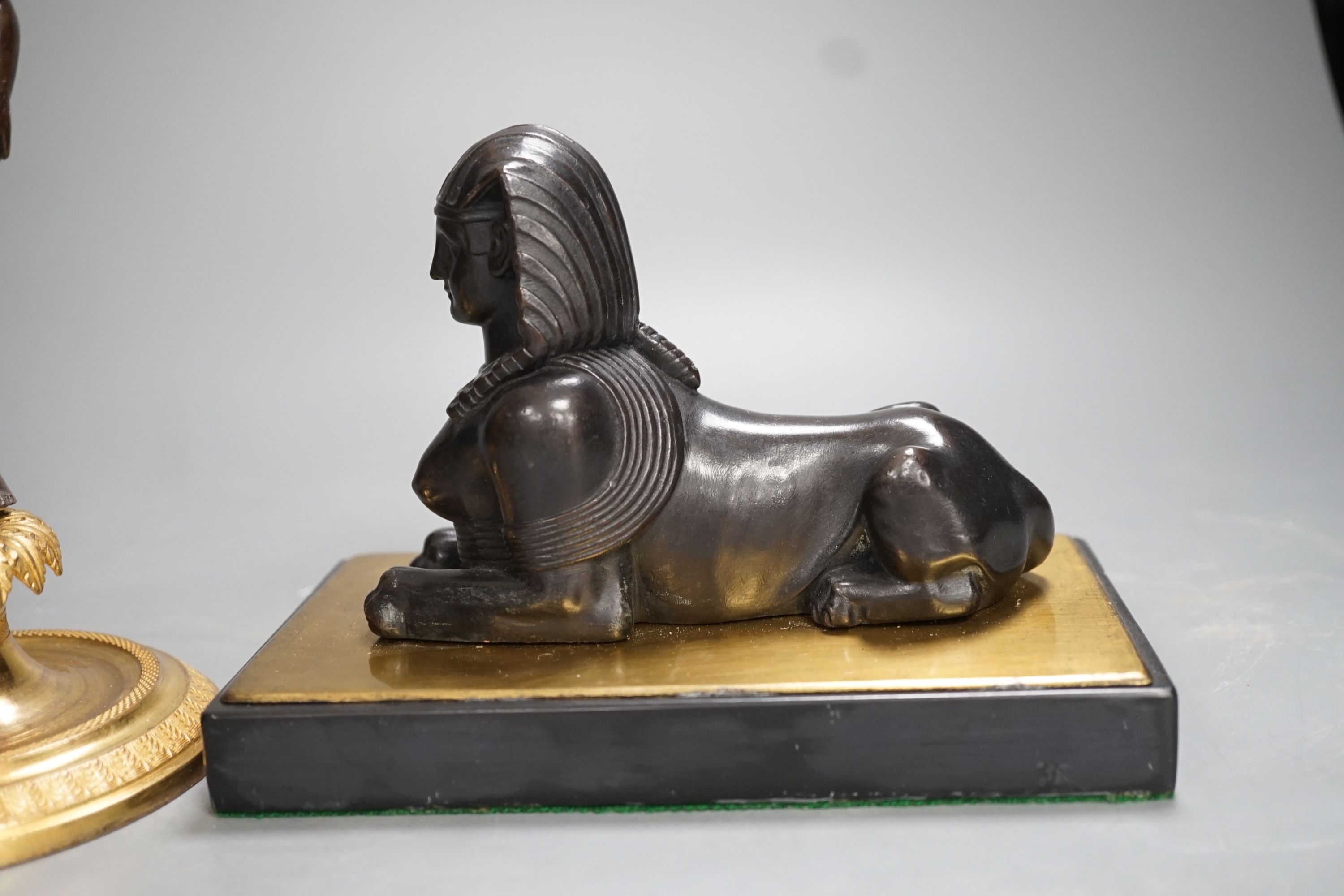 A patinated metal model of a sphinx and a bronze and gilt figure of a Nubian man. 22cm